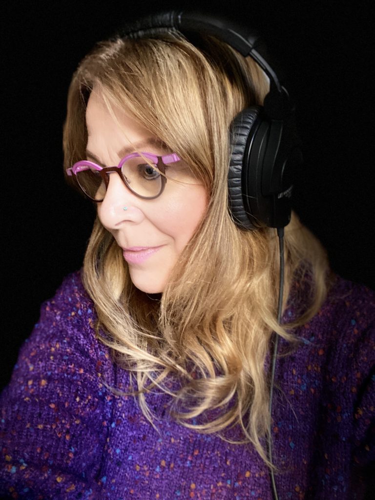 A photo of Phebe Phillips wearing a headset in a recording studio.